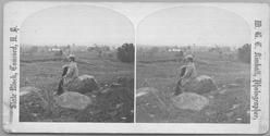 SA0070.1 - William Briggs sits on a rock in a field; buildings and stone walls are in the distance. Identified on the reverse. Modern photos derived from a stereograph., Winterthur Shaker Photograph and Post Card Collection 1851 to 1921c